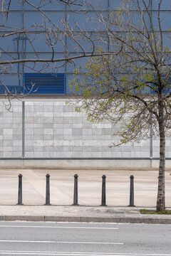 City sidewalk and bollards with empty space and blue wall backdrop. Minimalist urban design with linear composition, copy space, and contemporary structure in daylight setting.