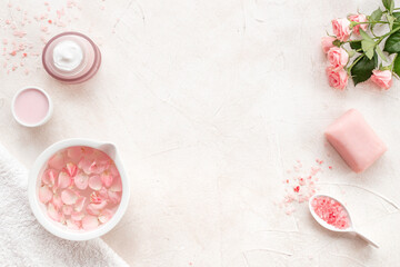 Beauty routine concept. Facial roses essence water and face cream with pink flowers and petals, top view