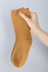 Woman with pair of socks on light grey background, closeup