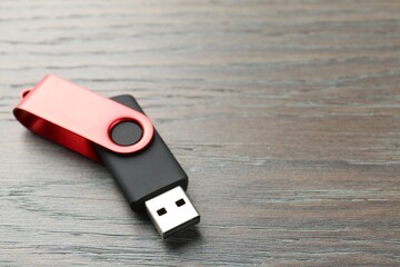 One flash drive on wooden background, closeup. Space for text