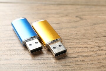 Two flash drives on wooden background, closeup. Space for text
