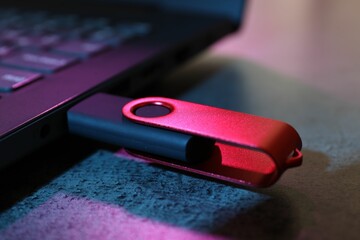 USB flash drive connected to laptop on dark grey table, closeup