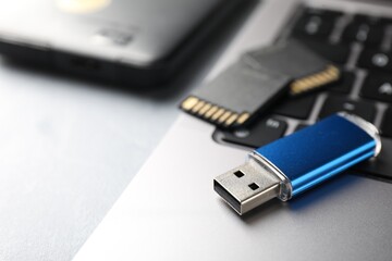 Flash drive, SD memory cards, external hard disk and laptop on light grey table, closeup. Space for text