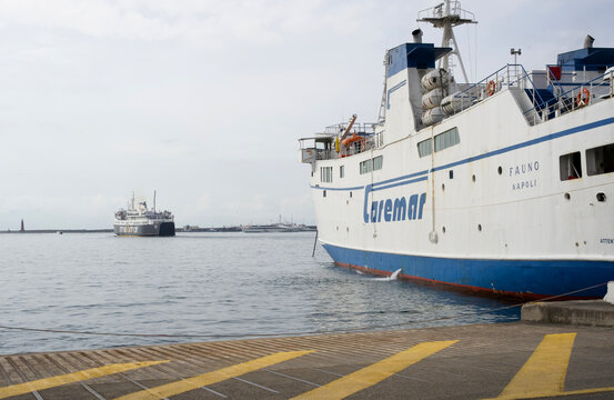 Naples, Italy - April 23, 2025: Large ferry named Caremar docked a harbor with another ship in the background, showcasing maritime transportation and the bustling port environment in Naples, Italy