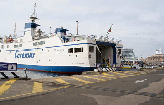 Naples, Italy - April 23, 2025: Caremar ferry docked at harbor, showcasing its blue and white design, with loading ramp extended, surrounded by calm waters and distant cruise ships
