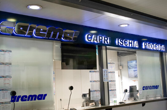 Naples, Italy - April 23, 2025: Caremar ferry ticket office displaying routes to Capri, Ischia, and Procida, featuring modern design elements and illuminated signage