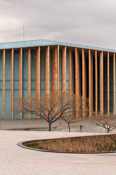Modern institutional building with wooden vertical fins and circular courtyard. Elegant geometry and warm textures define contemporary public architecture under soft daylight.