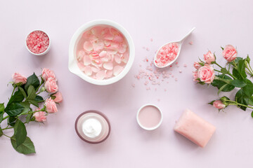 Homemade organic cosmetic with roses essential oil. Face cream with flowers and petals, top view