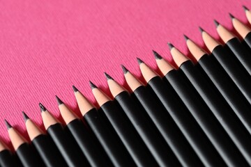 Many sharp graphite pencil on pink background, closeup