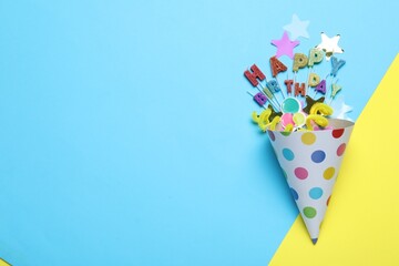 Beautiful party hat, topper and confetti on color background, flat lay. Space for text