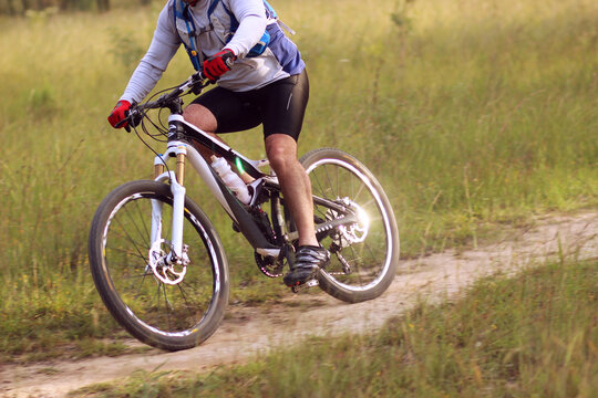 Close up of male cyclist riding pushbike on trail through paddock