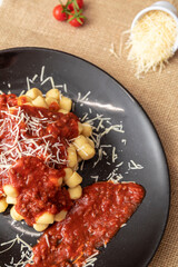 Close up on traditional italian potato gnocchi in tomato sauce with cheese and Cherry tomato