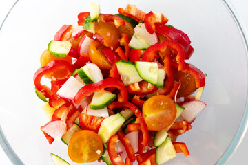 Fresh vegetable salad with cucumbers tomatoes and bell peppers in a clear bowl