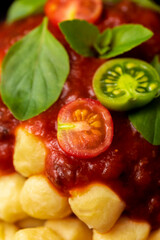Close up on traditional italian potato gnocchi in tomato sauce with fresh basil and Cherry tomato