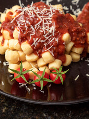 Close up on traditional italian potato gnocchi in tomato sauce with cheese and Cherry tomato