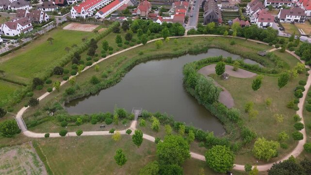 Orbit Around Unique Shaped Small Lake Surrounded by Green with Knokke Background | FlyLens 4K