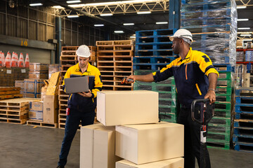 Warehouse operator maneuvers pallet jack to position stack of cardboard boxes for outgoing freight,...