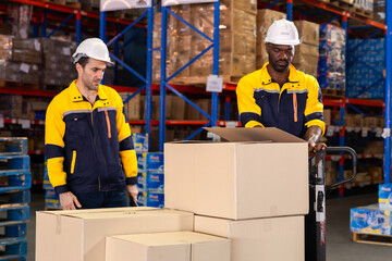 Warehouse technician kneels beside pallet to scan boxes with handheld scanner, checking barcodes...