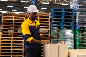Warehouse worker stacks cardboard boxes on pallet in logistics lane, preparing freight for dispatch...