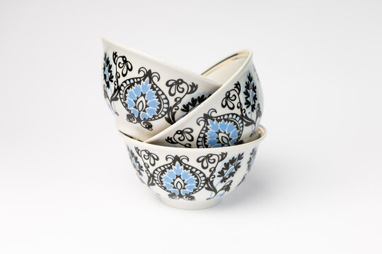 Traditional Uzbek tea bowls with ethnic floral ornament, isolated on white background. VIvid porcelain pialas cups for Asian restaurant tea ceremony.