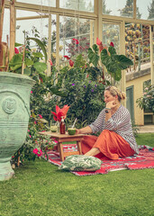 Woman sitting on carpet with drink in tropical garden cafe