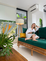 woman in a white coat sits on a green sofa