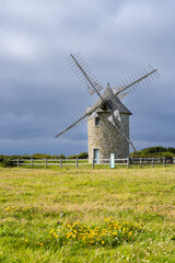 Old windmill standing in green field in Brittany, France