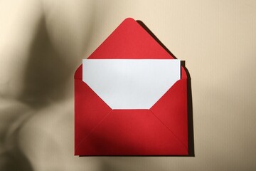 Blank greeting card and paper envelope on beige background, top view