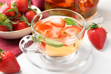 Aromatic fruit tea with strawberries and mint on white table, closeup