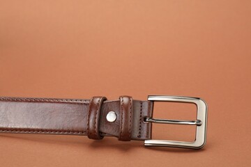 One leather belt on pale brown background, closeup