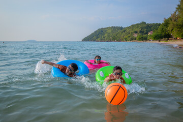 Obraz premium Children playing brightly colored inflatable rings joyful at the beach during playful and enjoying funny of summer semester vacations .