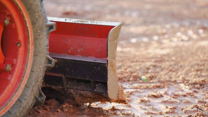 Heavy-duty agricultural equipment clearing wet soil on a farm.
