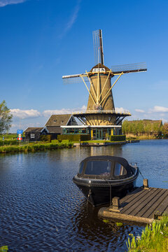 Traditional Dutch Windmill reflecting on the calm water of a canal in Bleskensgraaf, Netherlands