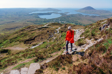 A hiker climbing Diamond Hill  in Connemara National Park, admiring the sweeping views of lakes, mountains, and lush Irish wilderness.