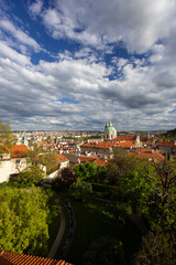 Fototapeta premium Panoramic view of Prague showing Vrtba Garden and St. Nicholas Church under cloudy sky