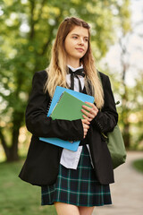 Fototapeta premium Stylish college girl enjoying a sunny campus day with her books and green bag