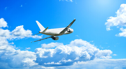 Passenger airplane flying in the sky, travel background with airplane flying high in the blue sky among clouds