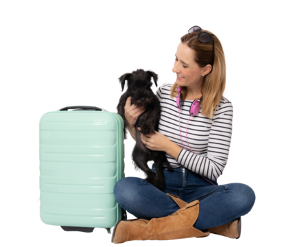 Young happy woman sitting on floor with her dog and suitcase isolated over transparent background. PNG transparent.