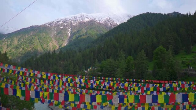 Colorful Buddhist prayer flags in front of the snowy Himalayan mountain peaks during a sunny day as seen on the way towards Triloknath temple in Pattan valley, Lahaul district, Himachal, India.