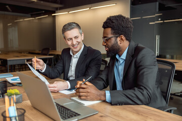 Two businessmen sitting in the office at the laptop and working on the project