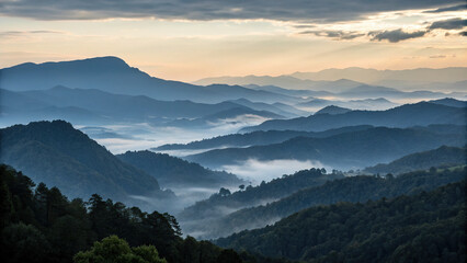 Obraz premium Breathtaking mountain range at twilight, showcasing layers of fog laden peaks and valleys, creating serene and tranquil atmosphere. soft light enhances natural beauty of landscape
