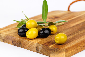 Rustic Mediterranean olives with olive twigs on wooden board over white background