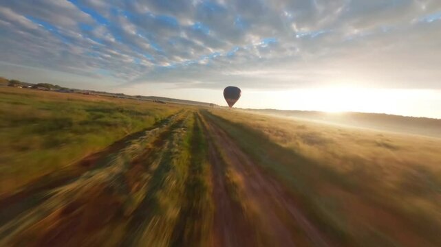 Hot air balloons in clear sky over field with people. Colorful balloons on aerial landscape background. Summer leisure. Hot air balloon in flight in the morning.