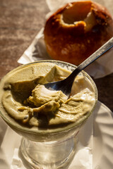Partially eaten Sicilian pistachio granita with spoon and brioche in warm light