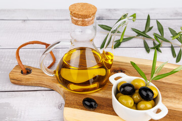 Olive oil lifestyle scene with natural olives and olive branches on wood over white background