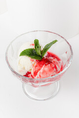 Savor a creamy ice cream bowl with sweet strawberry sauce and fresh mint