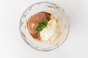Two scoops of creamy chocolate and vanilla ice cream sit in a crystal bowl with mint