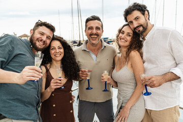 Happy friends toasting with champagne on a boat at the marina