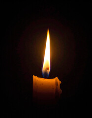 A single lit candle in a dark space symbolizes hope, guidance, and inner light during difficult times.