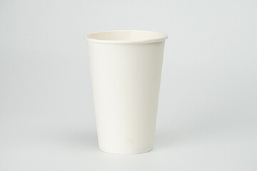 Single-use coffee cup on a flat surface, cylindrical body with ridges, lightweight material, small lid, neutral background, even lighting, commercial or informational style, straight-on perspective